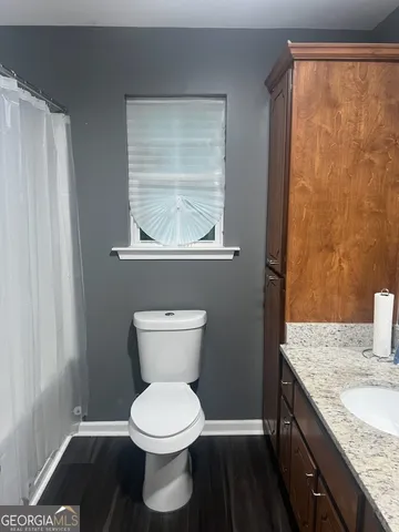 a bathroom with a granite countertop toilet and a sink