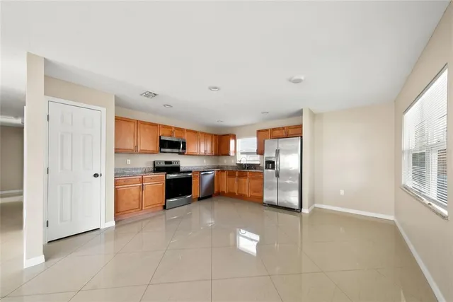 a large kitchen with stainless steel appliances kitchen island granite countertop a refrigerator and a sink