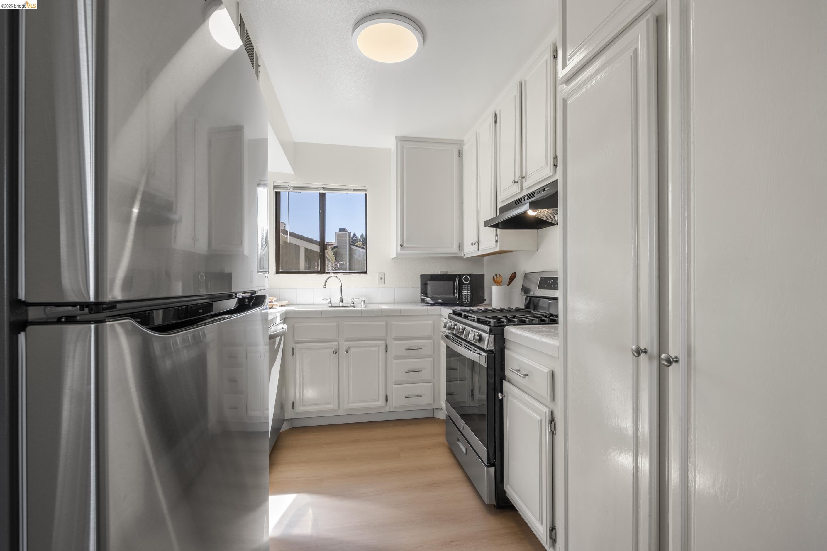 214 Apollo, Unit 3 Hercules, CA 94547 - Photo 6 of 26 Kitchen with stainless steel appliances, white cabinets, light countertops, and light wood-style floors
