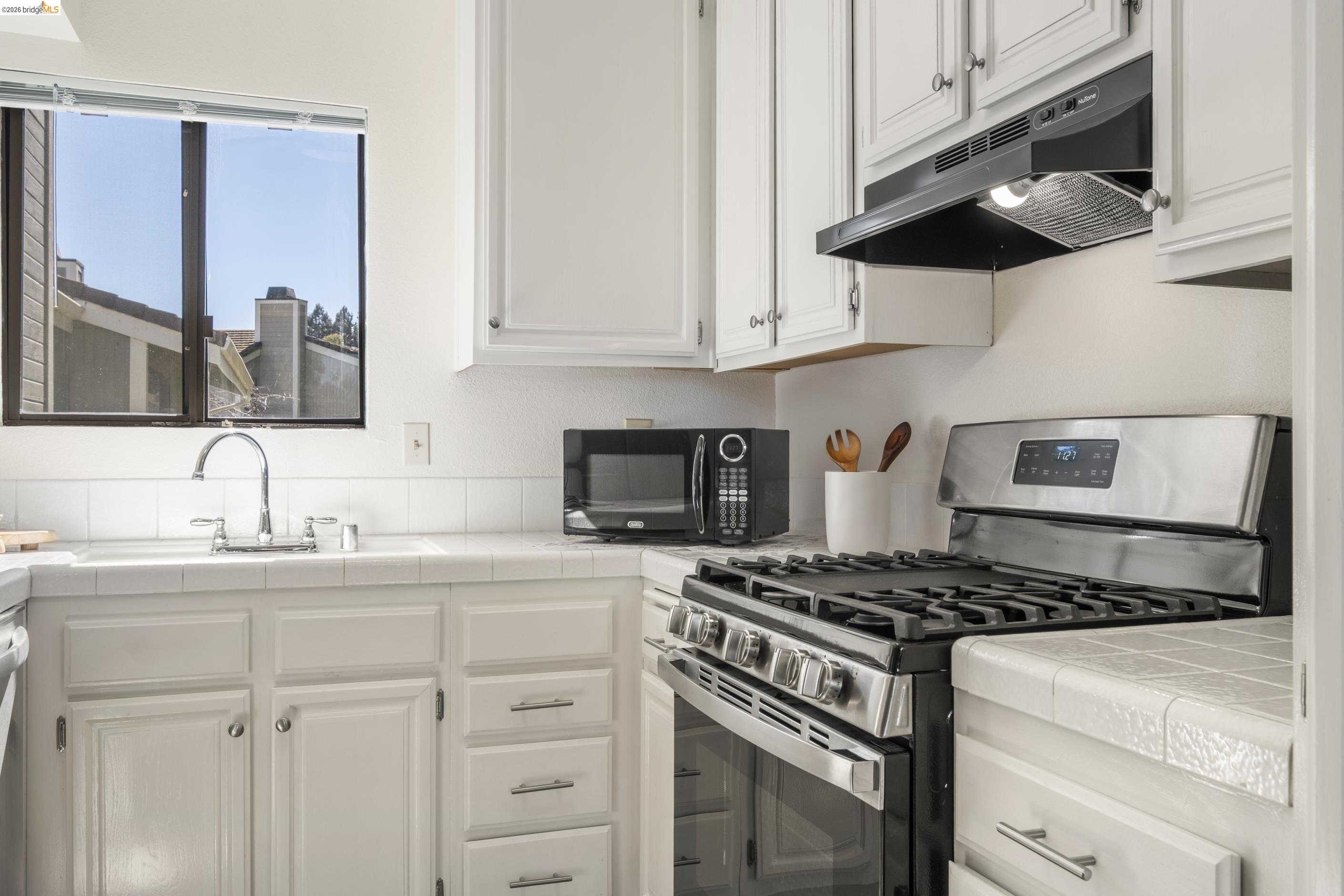 214 Apollo, Unit 3 Hercules, CA 94547 - Photo 7 of 26 Kitchen featuring stainless steel gas stove, tile counters, white cabinets, and black microwave
