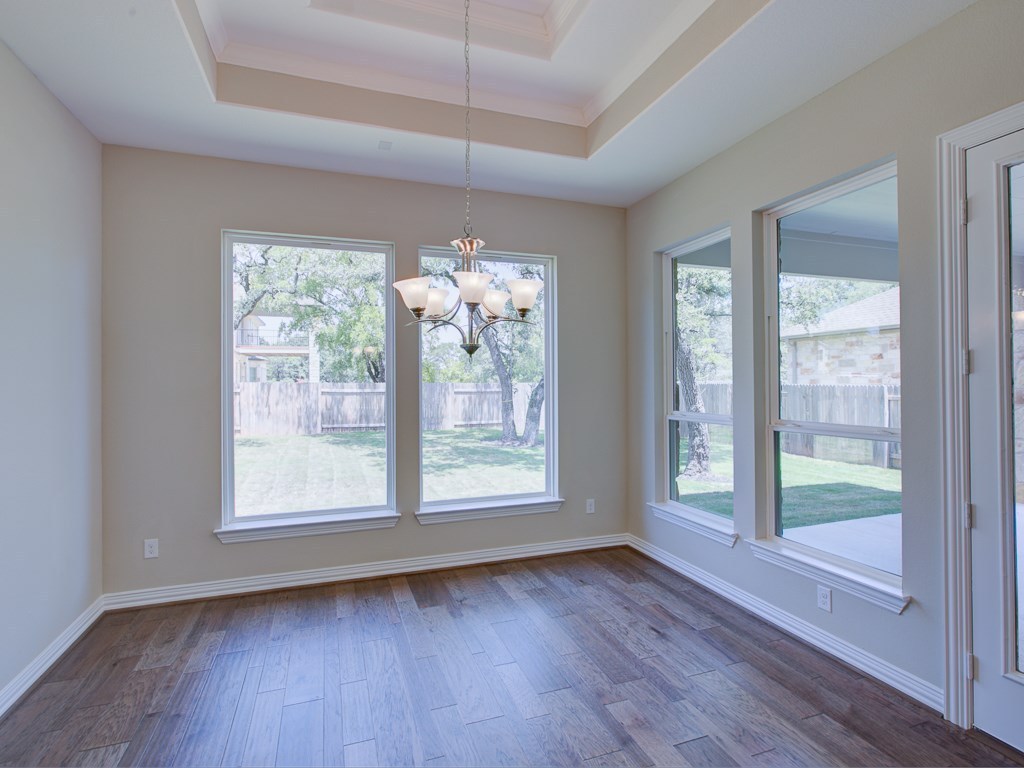 4303 Logan Ridge Drive Cedar Park, TX 78613 - Photo 8 of 24 Spacious room featuring wood-finish flooring, a tray ceiling, and a chandelier with glass shades