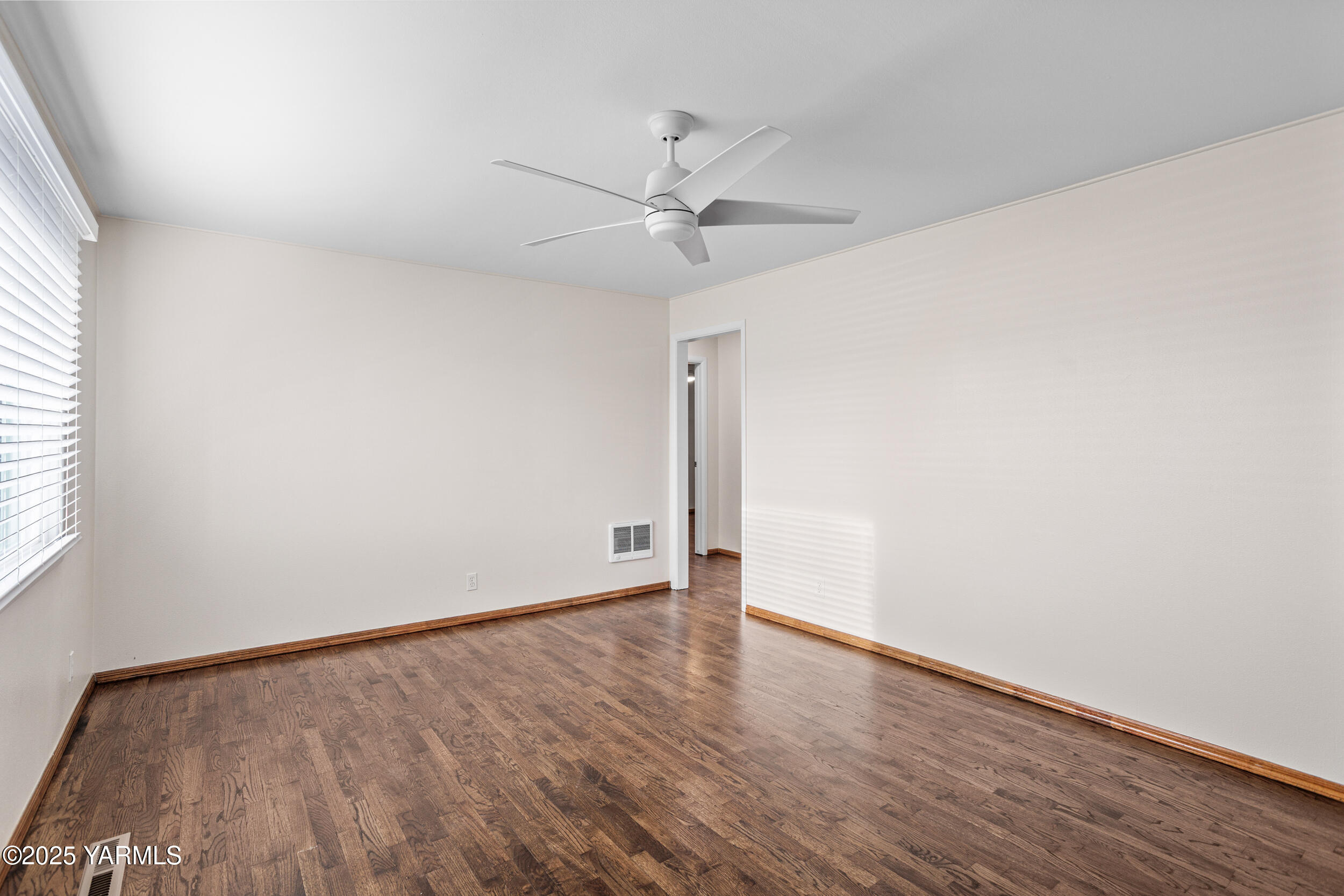 814 Adams Avenue Toppenish, WA 98948 - Photo 18 of 23 an empty room with wooden floor fan and windows