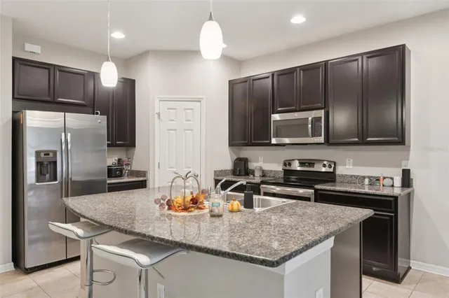 a kitchen with kitchen island granite countertop stainless steel appliances cabinets a sink and a center island