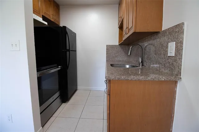 a kitchen with granite countertop a refrigerator and a sink