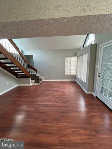 a view of an empty room with wooden floor and stairs