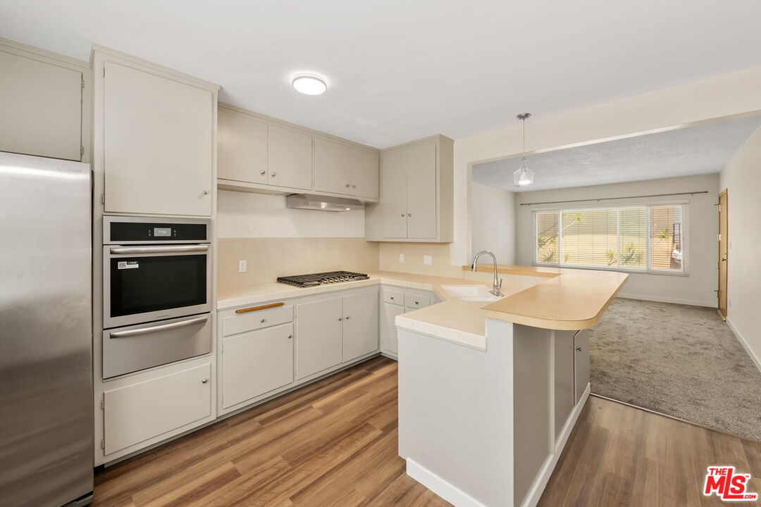8335 West Manchester Avenue, Unit D Playa del Rey, CA 90293 - Photo 9 of 17 a kitchen with a sink a stove a refrigerator and white cabinets