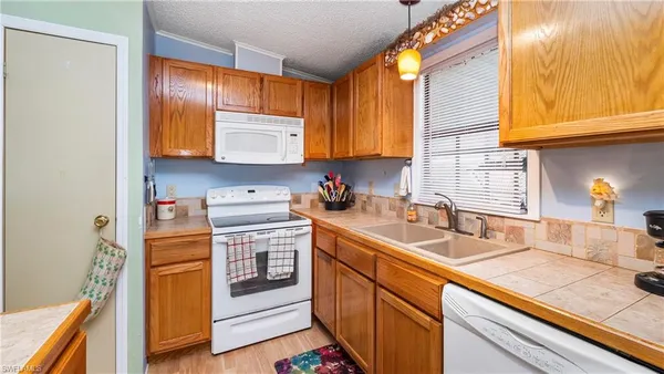 a kitchen with stainless steel appliances granite countertop a sink dishwasher and a refrigerator with wooden floor