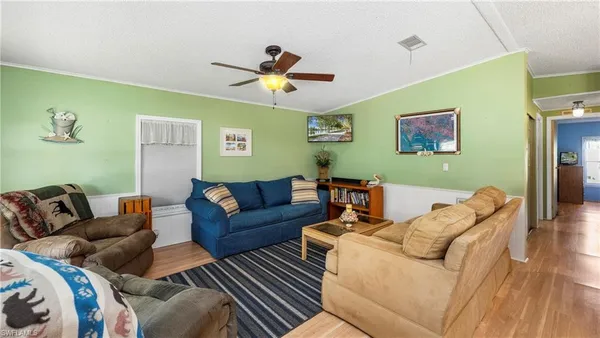 a living room with furniture kitchen view and a chandelier