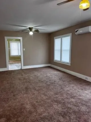 an empty room with windows and fan