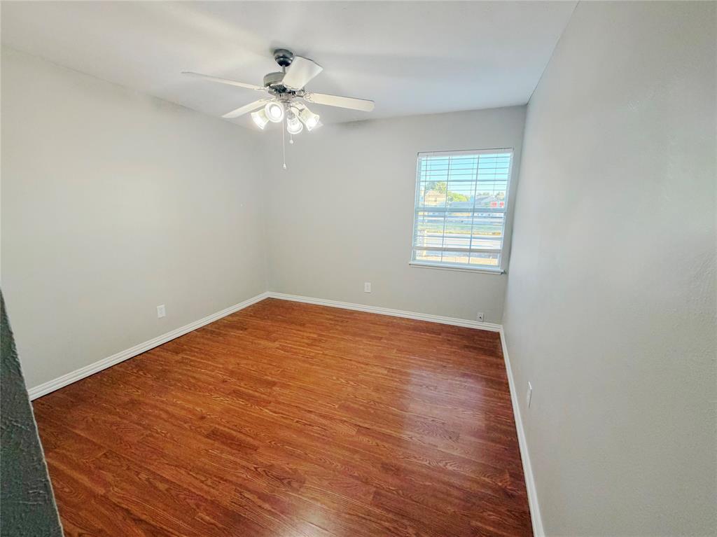 8601 Woodside Road Rowlett, TX 75088 - Photo 16 of 22 Wood-finish flooring, white baseboards, a window with blinds, and a ceiling fan with integrated lighting