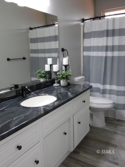 208 South Greenlawn Street Ridgecrest, CA 93555 - Photo 13 of 29 a bathroom with a granite countertop sink a toilet and shower