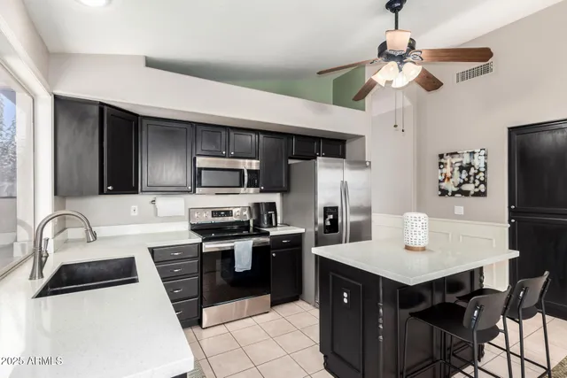 a kitchen with stainless steel appliances a sink a stove a refrigerator cabinets and a dining table