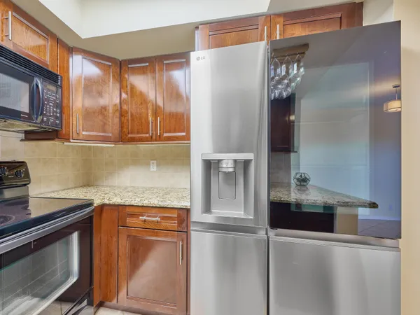 a kitchen with granite countertop a refrigerator and a stove top oven