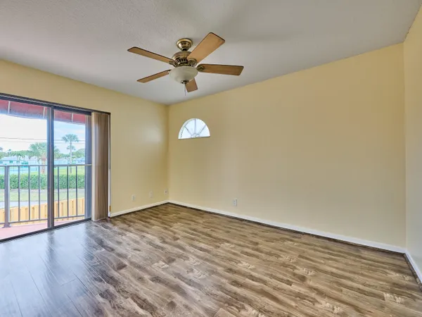 a view of an empty room with wooden floor and a window