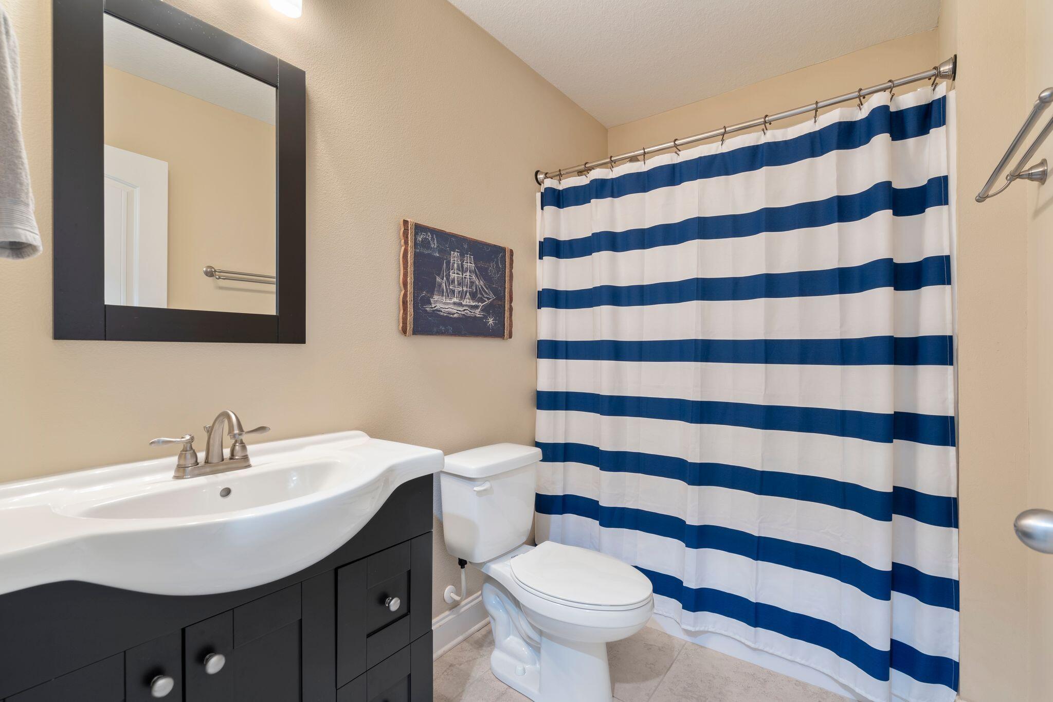 2933 Chancel Avenue Crestview, FL 32539 - Photo 17 of 44 a bathroom with a sink a toilet a mirror and shower curtain