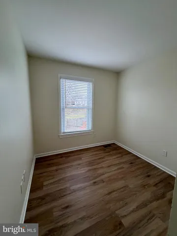 a view of an empty room with wooden floor and closet