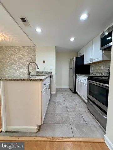 a kitchen with stainless steel appliances granite countertop a sink stove and cabinets