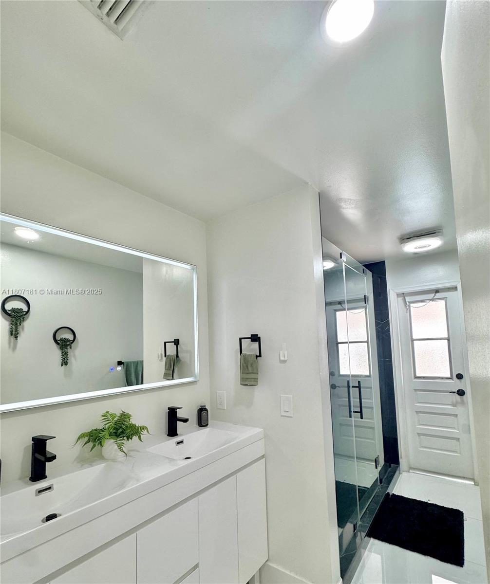 15421 Southwest 158th Street Miami, FL 33187 - Photo 12 of 31 a bathroom with a sink a mirror and a shower