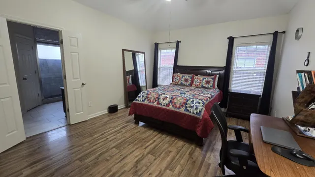 a bedroom with a bed a mirror and wooden floor