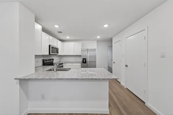 a kitchen with stainless steel appliances granite countertop a sink refrigerator stove and microwave