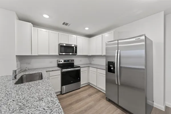 a kitchen with granite countertop a refrigerator and a sink