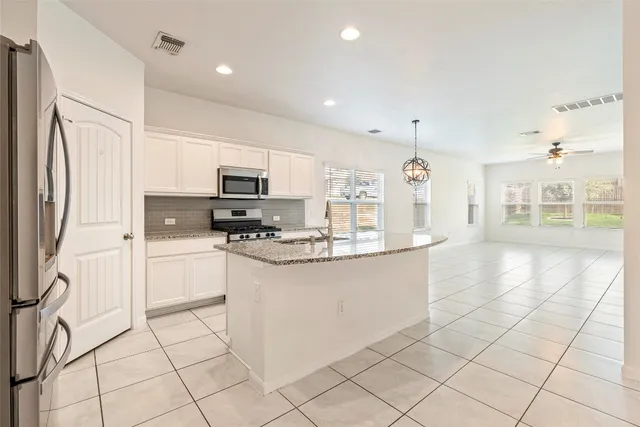 a large kitchen with granite countertop a large counter top stainless steel appliances and cabinets