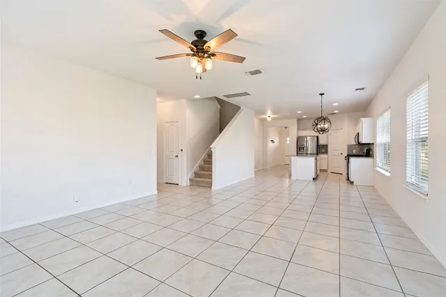 a view of an empty room and a chandelier fan