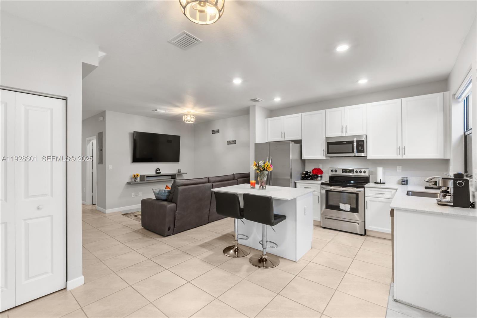 a living room with furniture a flat screen tv and kitchen view