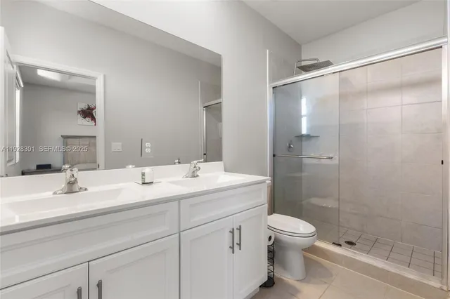 a bathroom with a double vanity sink toilet mirror and shower