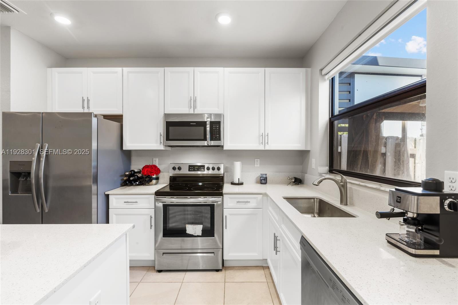 9917 Southwest 228th Terrace Miami, FL 33190 - Photo 33 of 36 a kitchen with a sink white cabinets and stainless steel appliances