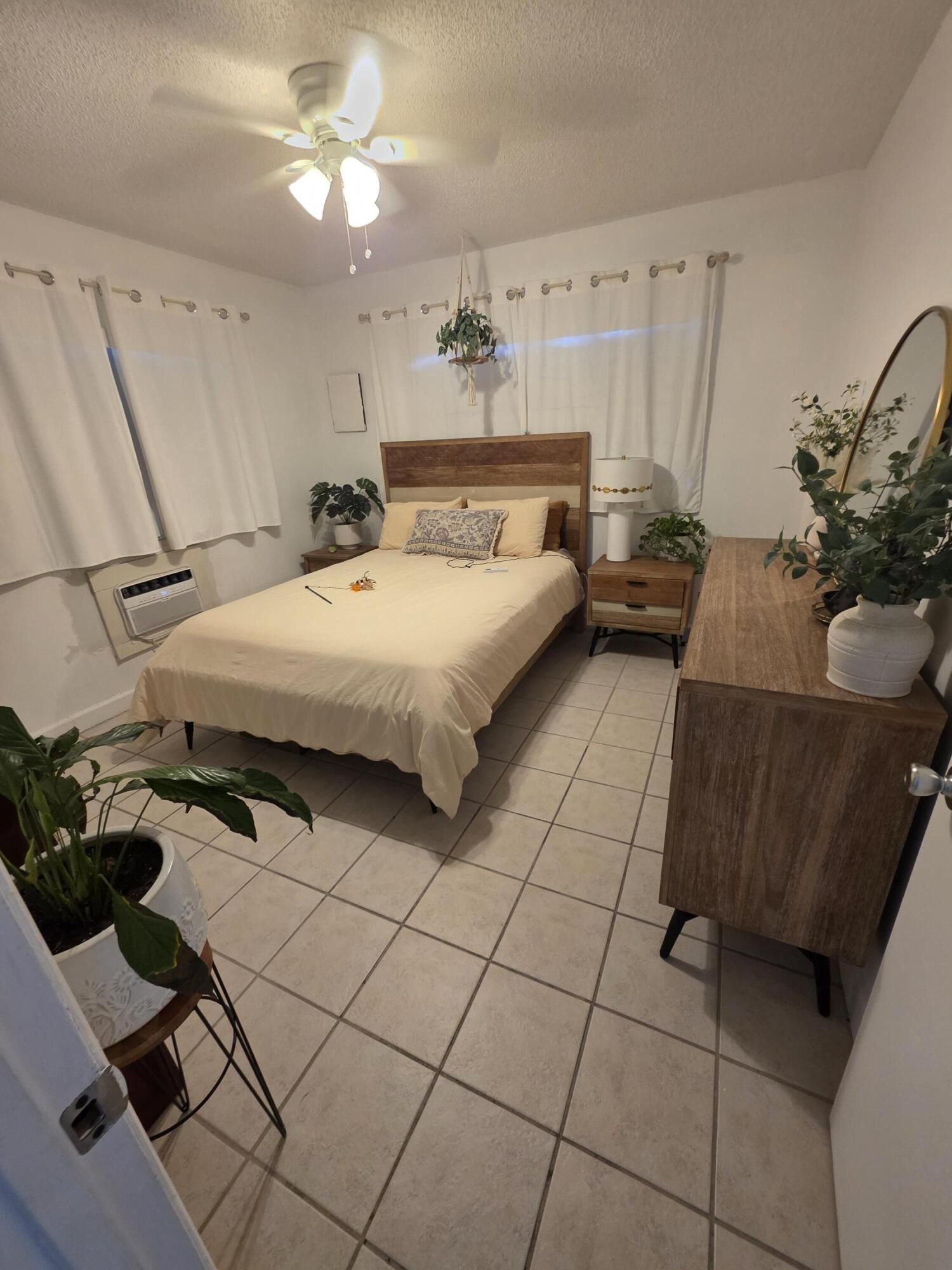 217 Butler Street, Unit 1 West Palm Beach, FL 33407 - Photo 2 of 9 a spacious bedroom with a bed and a chandelier