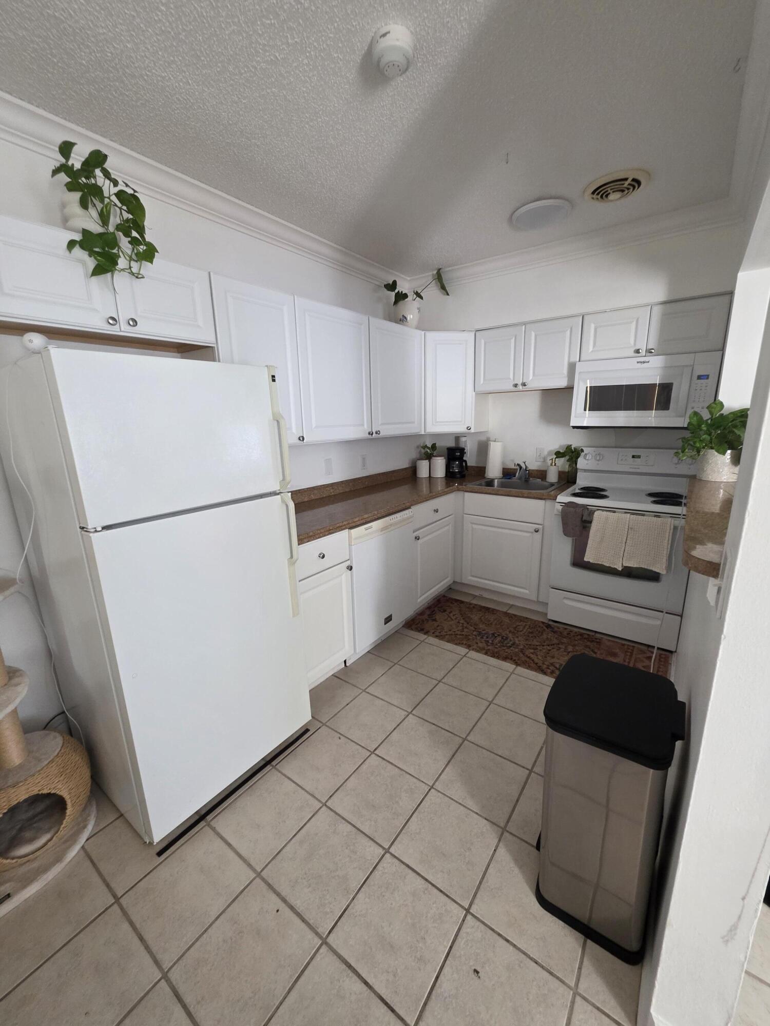 217 Butler Street, Unit 1 West Palm Beach, FL 33407 - Photo 6 of 9 a kitchen with white cabinets and white appliances