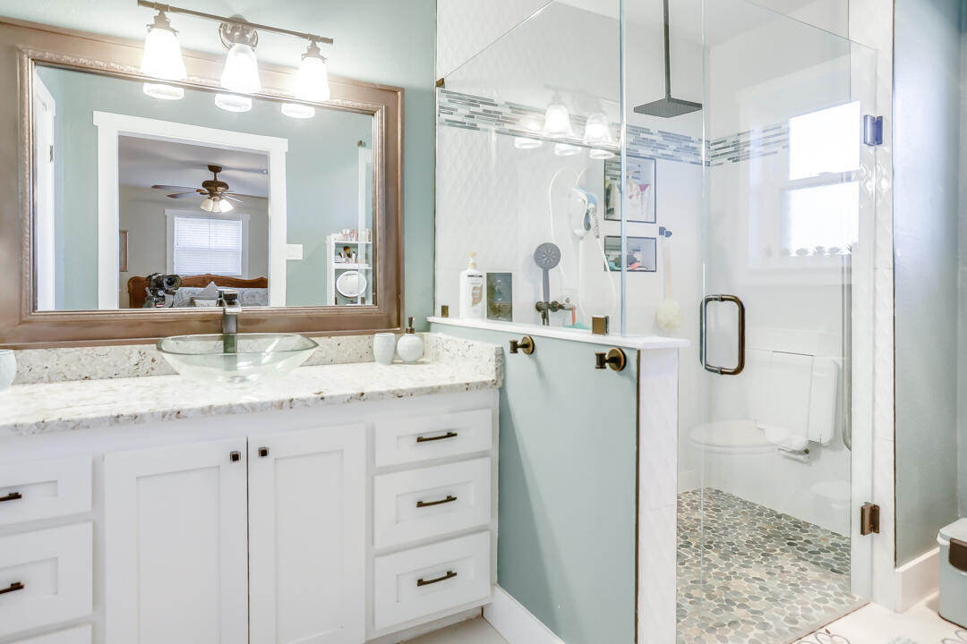 4306 57th Street Lubbock, TX 79413 - Photo 22 of 23 a bathroom with a granite countertop sink vanity mirror and shower