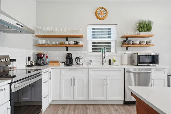a kitchen with stainless steel appliances granite countertop a stove a sink and a microwave
