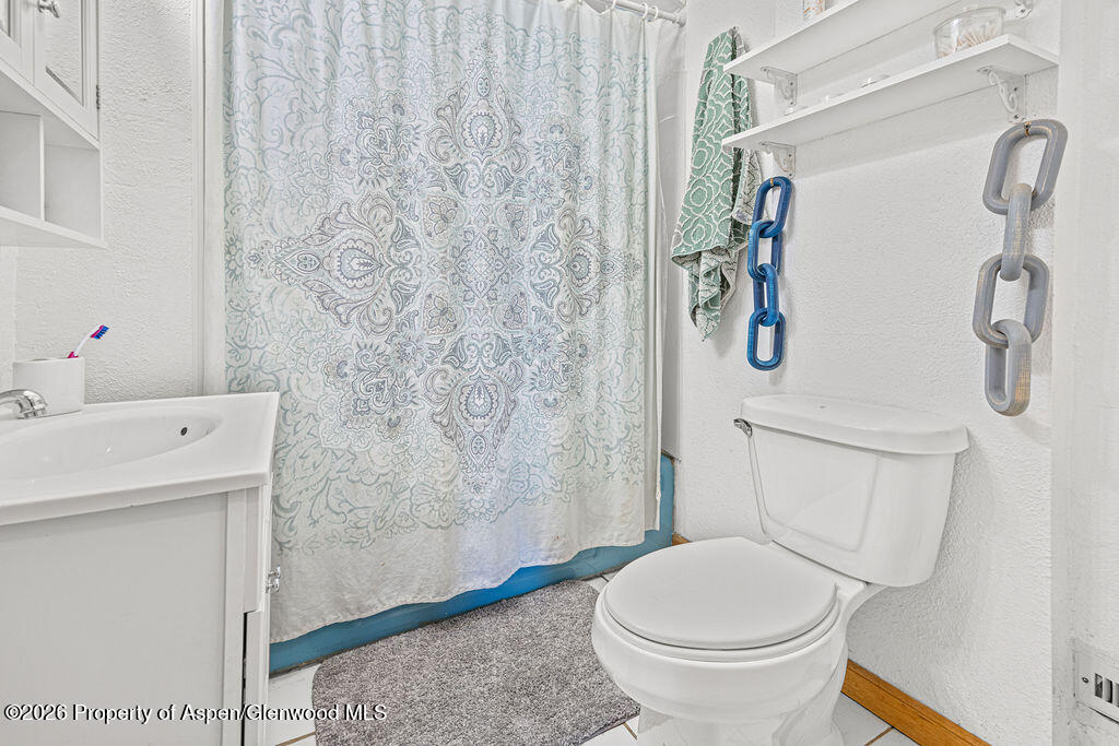 604 Tucker Street Craig, CO 81625 - Photo 17 of 35 a bathroom with a toilet and a shower curtain