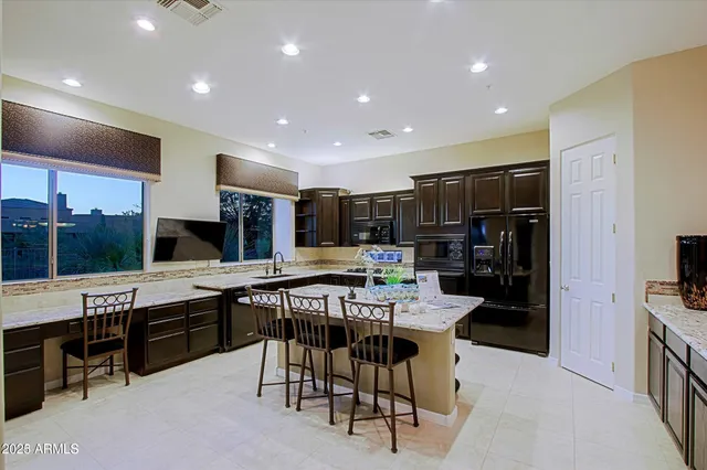 a kitchen with stainless steel appliances kitchen island granite countertop a table chairs sink and cabinets