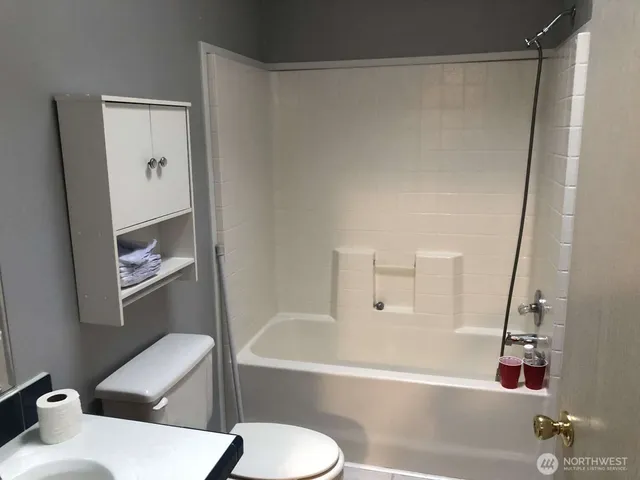 a bathroom with a tub shower sink and toilet