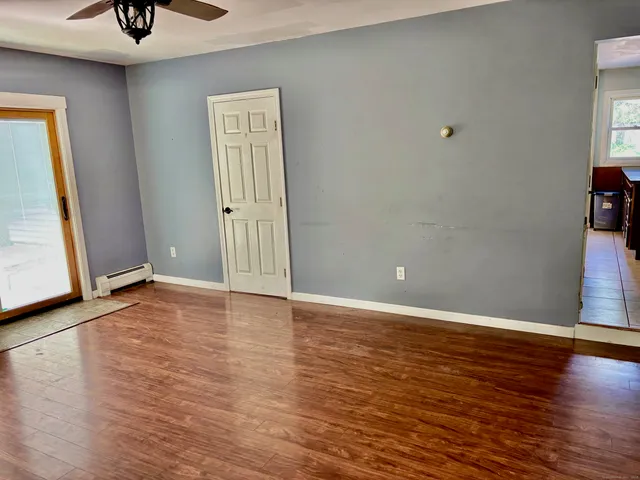 a view of an empty room with window and wooden floor