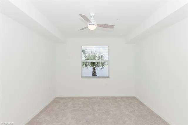 an empty room with window and ceiling fan