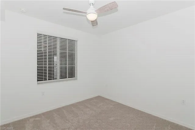 an empty room with a window and ceiling fan