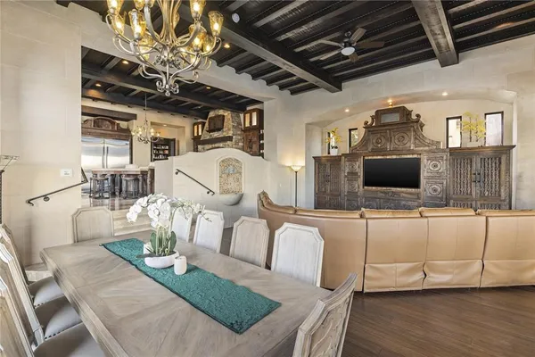 a dining room with wooden floor a chandelier a wooden table and chairs