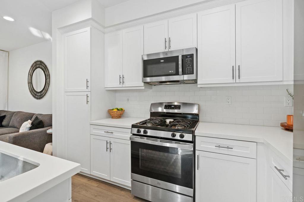 305 Cricket Court Santee, CA 92071 - Photo 4 of 25 a kitchen with white cabinets a sink and a stove with wooden floors