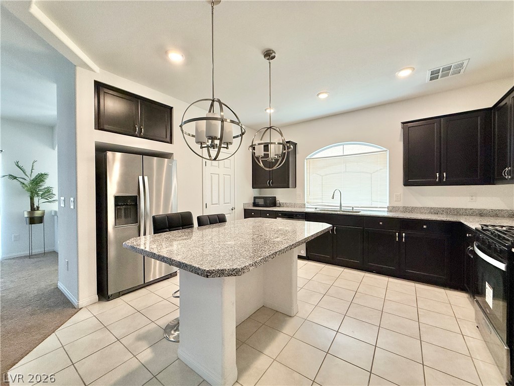 7777 South Westwind Road Las Vegas, NV 89139 - Photo 22 of 46 Prepare meals in this kitchen featuring dark cabinetry, ample counter space, and a functional island.