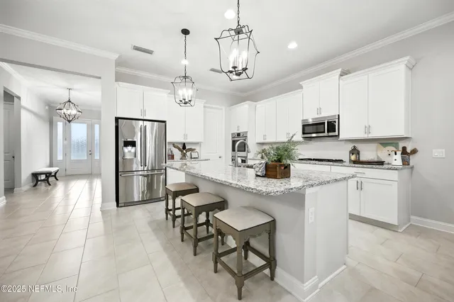 a kitchen with stainless steel appliances kitchen island granite countertop a refrigerator a stove a sink a dining table and chairs with wooden floor