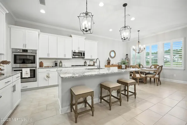 a open kitchen with stainless steel appliances granite countertop a sink dishwasher a stove a kitchen island with chairs and cabinets