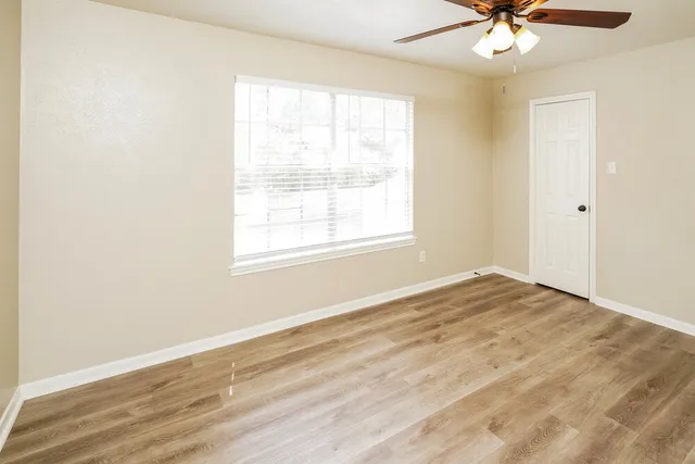 an empty room with windows and fan