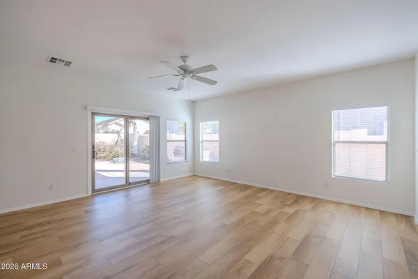 a view of an empty room with wooden floor and a window