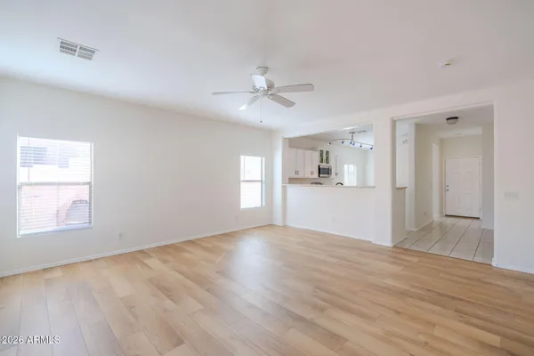 a view of an empty room with a kitchen and wooden floor