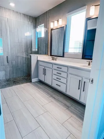 a spacious bathroom with a double vanity sink a mirror and a shower
