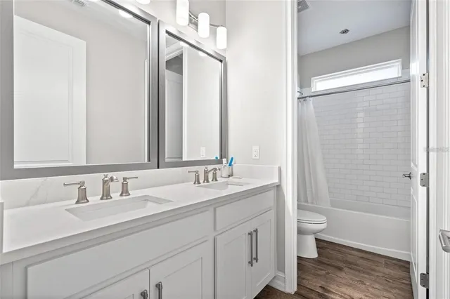 a bathroom with a double vanity sink a toilet and a large mirror
